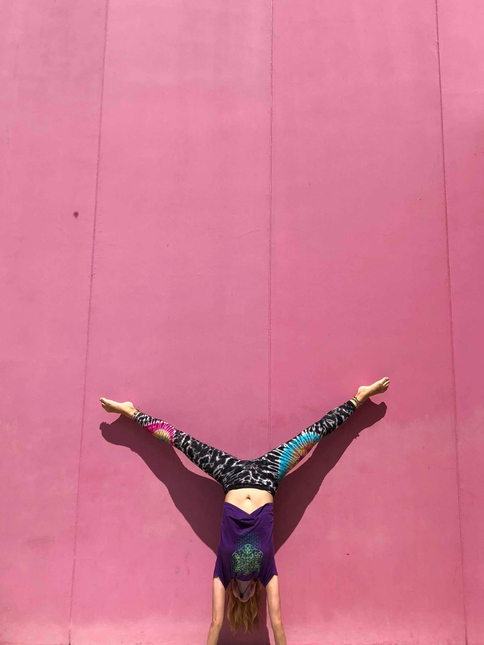 Handstand in front of a pink wall